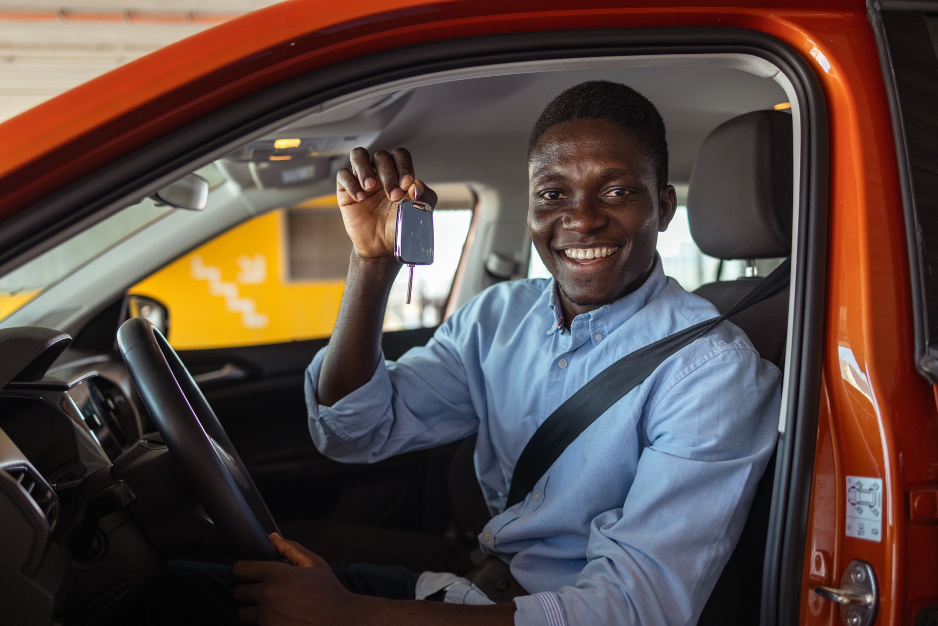 Young man holding car keys in the driver's seat